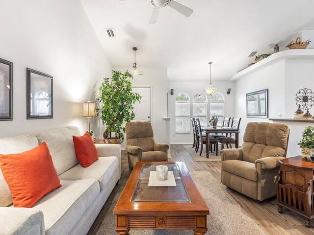 living room with ceiling fan, lofted ceiling, and light hardwood / wood-style floors