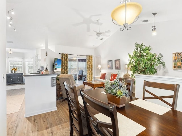 dining space with ceiling fan, lofted ceiling, and light hardwood / wood-style flooring