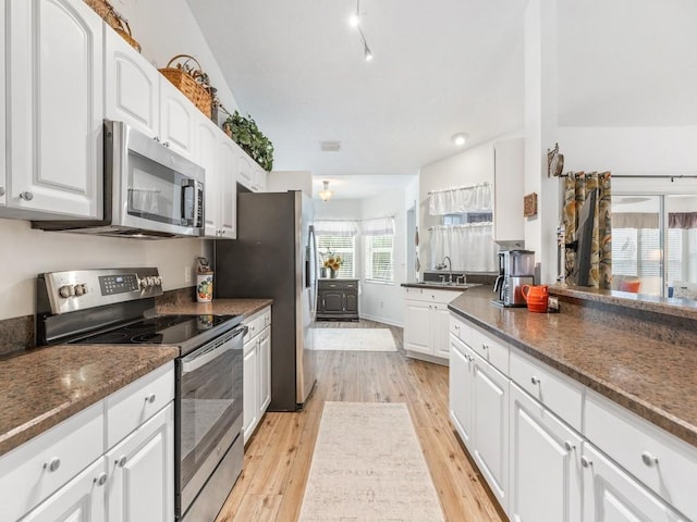 kitchen featuring stainless steel appliances, sink, light hardwood / wood-style flooring, and white cabinets