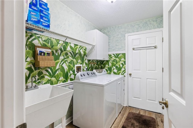 laundry room featuring separate washer and dryer, sink, cabinets, a textured ceiling, and light wood-type flooring