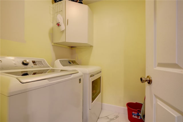 clothes washing area with cabinets and washing machine and clothes dryer