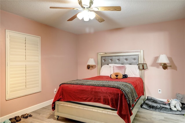 bedroom with light hardwood / wood-style floors, ceiling fan, and a textured ceiling