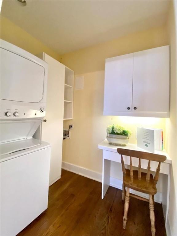 laundry area featuring cabinets, stacked washer and clothes dryer, and dark hardwood / wood-style flooring