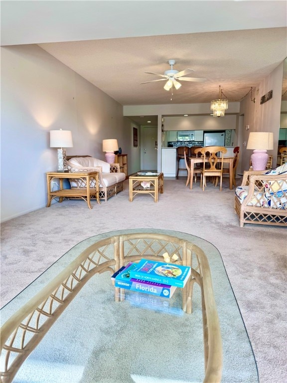 carpeted living room featuring ceiling fan with notable chandelier