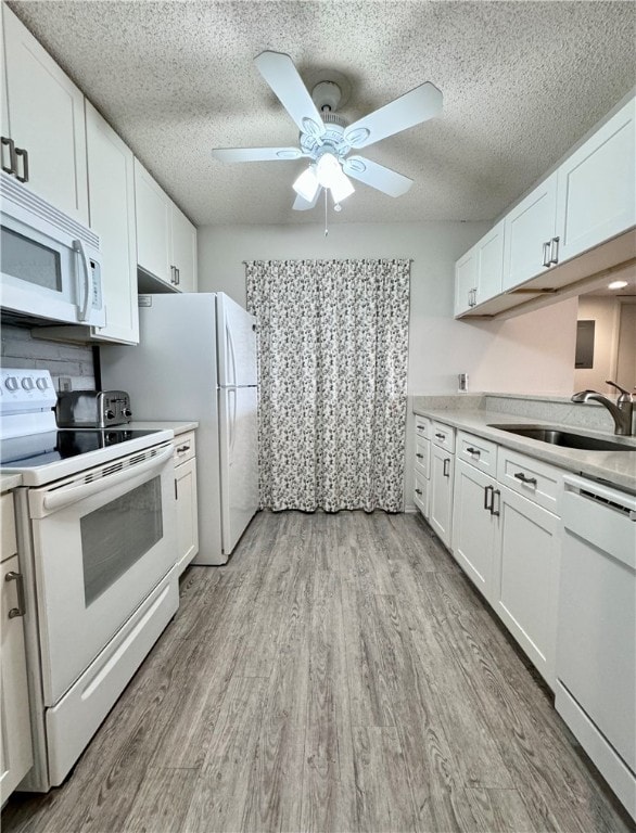 kitchen with white appliances, light hardwood / wood-style floors, white cabinetry, and sink