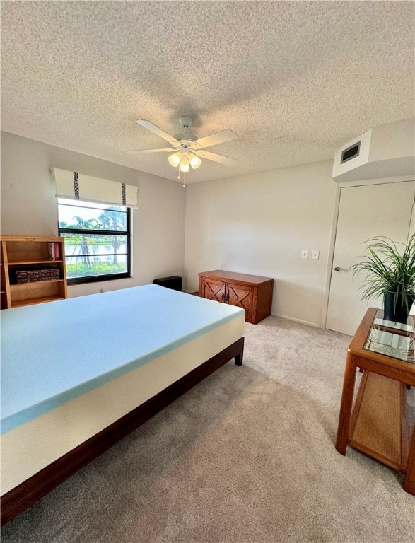 bedroom featuring a textured ceiling, ceiling fan, and light carpet