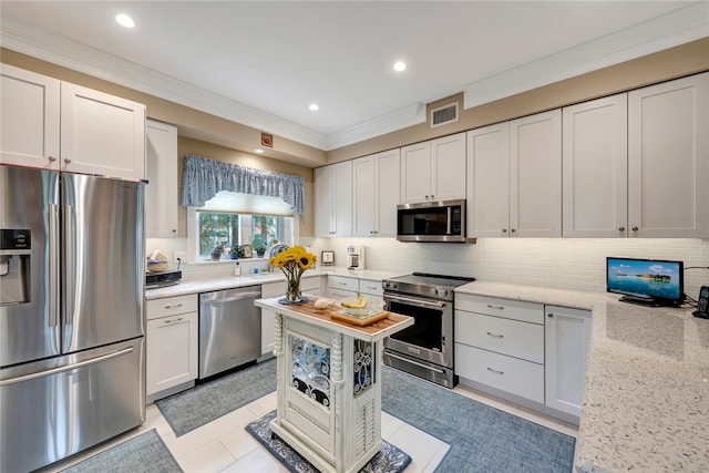 kitchen featuring light stone countertops, white cabinetry, appliances with stainless steel finishes, and ornamental molding