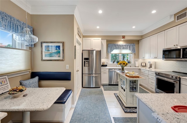 kitchen featuring pendant lighting, a kitchen bar, stainless steel appliances, and white cabinetry