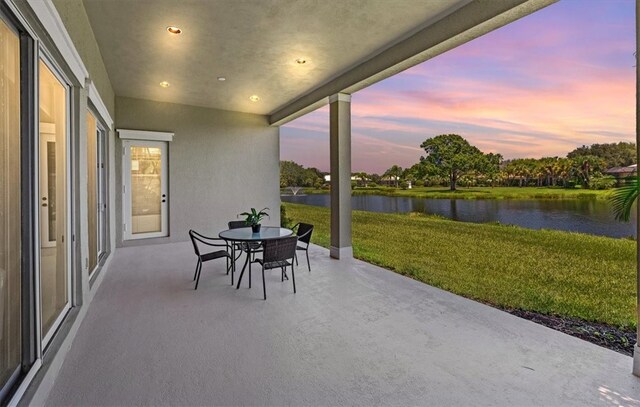 patio terrace at dusk with a yard and a water view