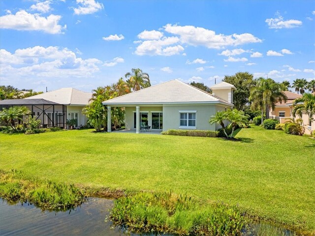 rear view of house featuring a yard, a water view, and a patio