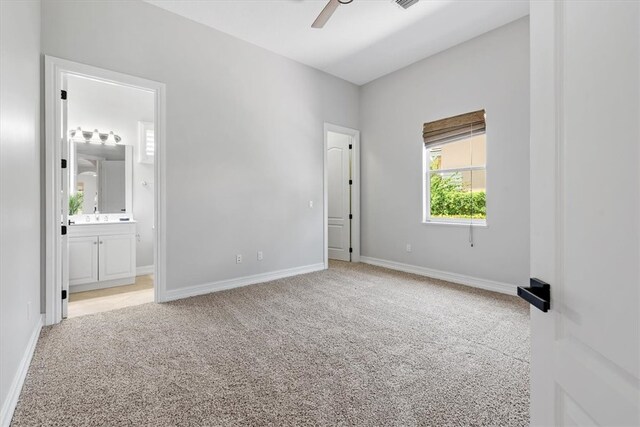 unfurnished bedroom with light carpet, connected bathroom, and ceiling fan