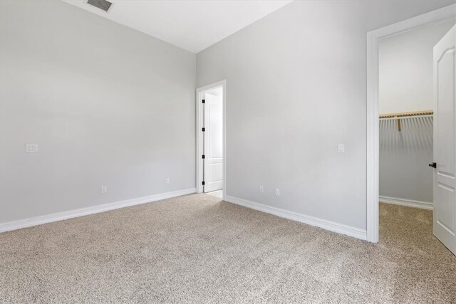 unfurnished bedroom featuring carpet, a walk in closet, and a closet