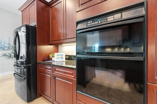 kitchen with black appliances, dark stone countertops, light tile patterned floors, and ornamental molding