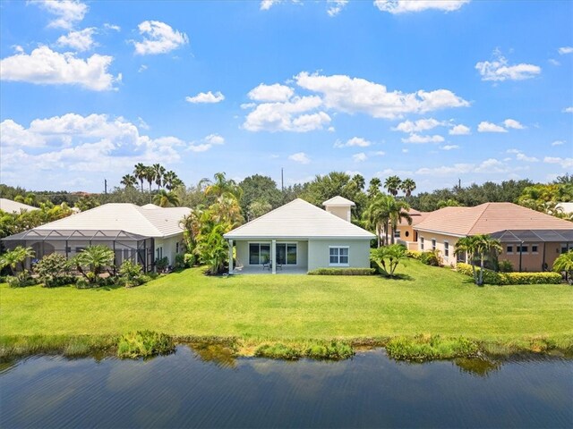 rear view of house with a water view and a lawn