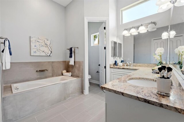 bathroom with tile patterned floors, toilet, plenty of natural light, and tiled tub