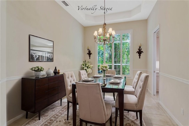 dining area with visible vents, baseboards, an inviting chandelier, a tray ceiling, and light tile patterned flooring