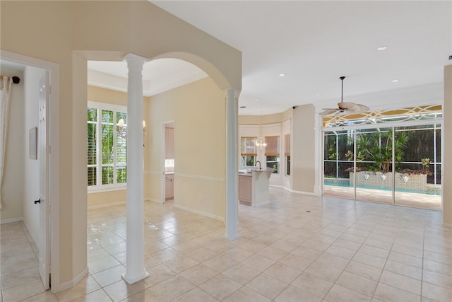 unfurnished room featuring arched walkways, light tile patterned flooring, a ceiling fan, baseboards, and decorative columns