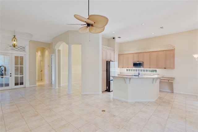 839 Island Club Sq, Vero Beach, FL 32963 - kitchen featuring stainless steel appliances, open floor plan, light brown cabinets, arched walkways, and a ceiling fan