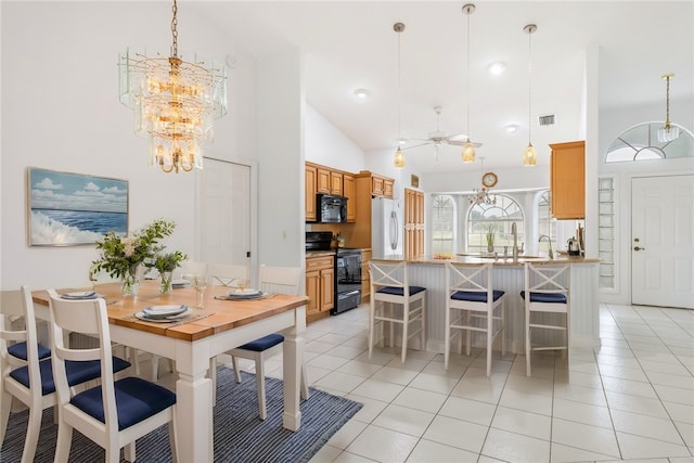 tiled dining area with high vaulted ceiling and ceiling fan with notable chandelier