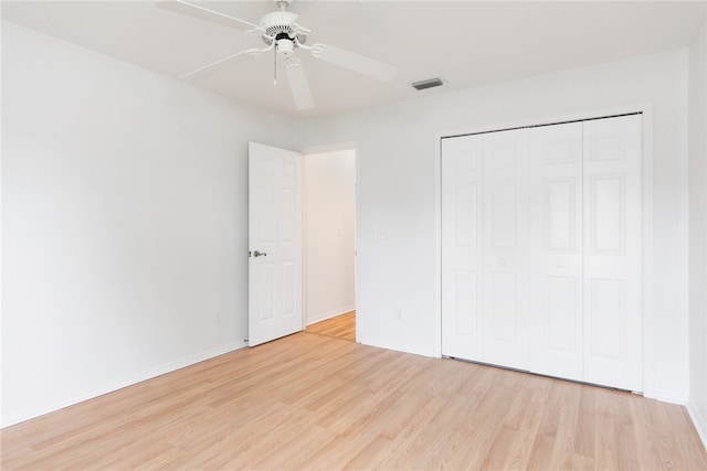 unfurnished bedroom featuring ceiling fan, a closet, and light wood-type flooring