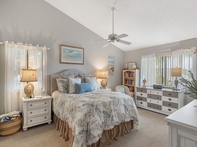 bedroom with lofted ceiling, a textured ceiling, light colored carpet, and ceiling fan