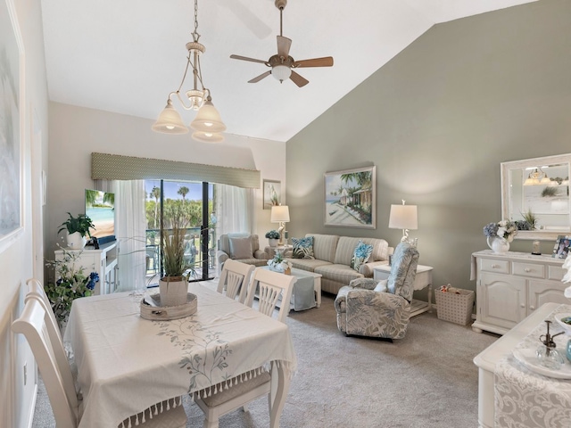 carpeted dining space featuring ceiling fan with notable chandelier and high vaulted ceiling