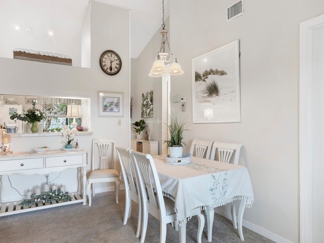 carpeted dining area featuring high vaulted ceiling and a notable chandelier