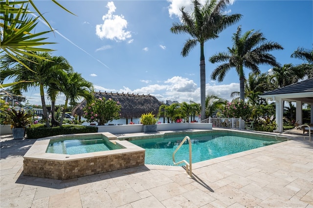 outdoor pool with an in-ground hot tub and a patio