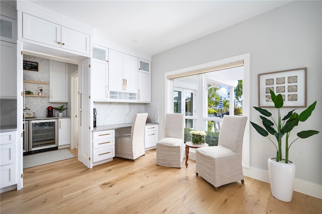 living area with wine cooler, light wood-style floors, and baseboards