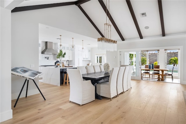 dining space featuring high vaulted ceiling, beam ceiling, and light wood-style flooring
