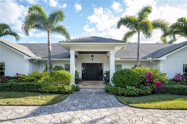 doorway to property featuring stucco siding and a tiled roof