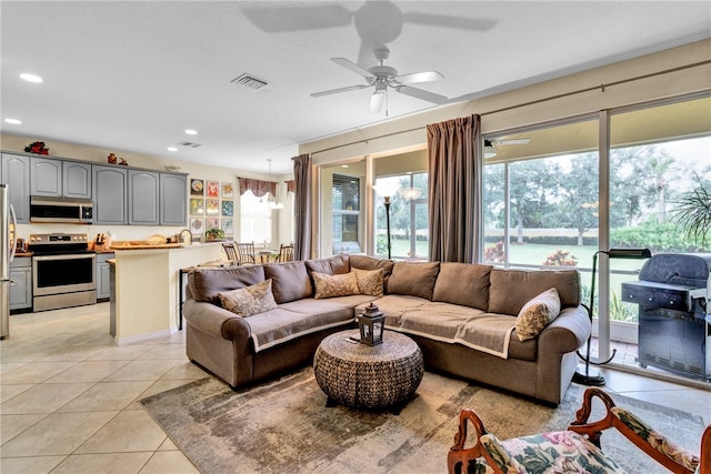 tiled living room with ceiling fan with notable chandelier