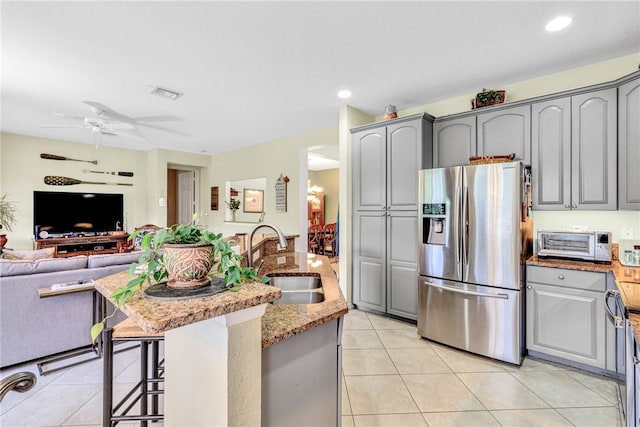 kitchen featuring gray cabinets, sink, stainless steel fridge with ice dispenser, and a breakfast bar area