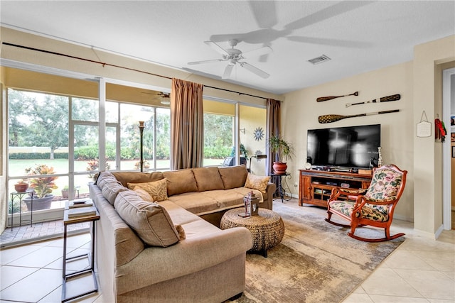 tiled living room with a water view, a textured ceiling, and ceiling fan