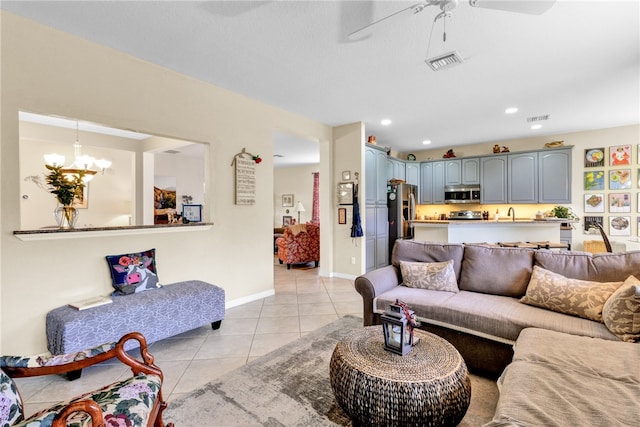 living room featuring ceiling fan with notable chandelier and light tile patterned floors