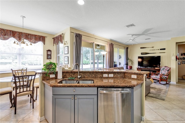 kitchen with dark stone counters, sink, gray cabinetry, stainless steel dishwasher, and pendant lighting