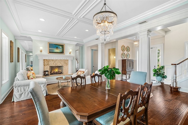 dining space with ornate columns, coffered ceiling, a high end fireplace, dark hardwood / wood-style floors, and ornamental molding