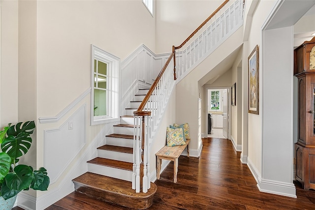 staircase featuring hardwood / wood-style flooring and a towering ceiling