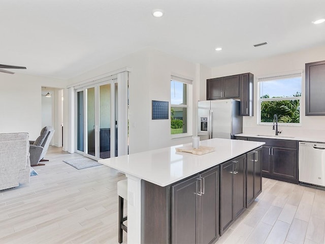 kitchen featuring ceiling fan, sink, dishwasher, stainless steel fridge with ice dispenser, and a center island