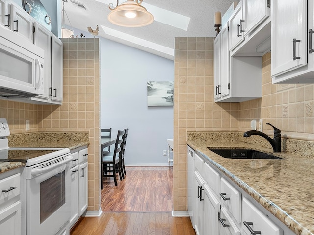 kitchen with white cabinetry, sink, a textured ceiling, white appliances, and light wood-type flooring