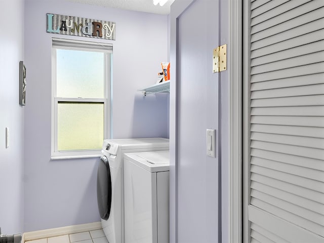 clothes washing area featuring separate washer and dryer, a wealth of natural light, light tile patterned floors, and a textured ceiling