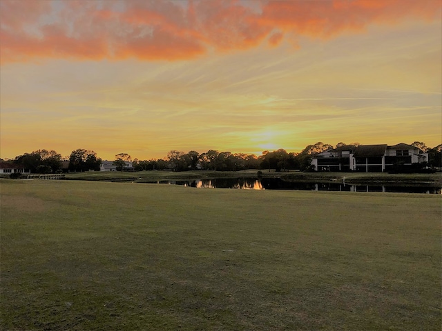 yard at dusk featuring a water view