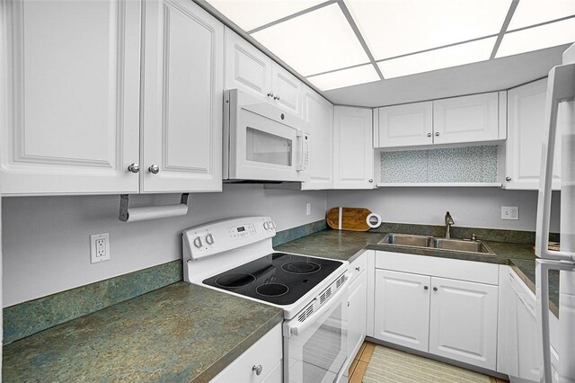 1901 Indian River Blvd Unit 202D, Vero Beach, FL 32960 - kitchen with white appliances, white cabinetry, and dark countertops
