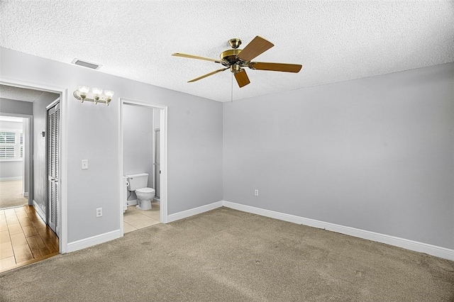 1901 Indian River Blvd Unit 202D, Vero Beach, FL 32960 - unfurnished bedroom featuring carpet flooring, a textured ceiling, connected bathroom, and a ceiling fan
