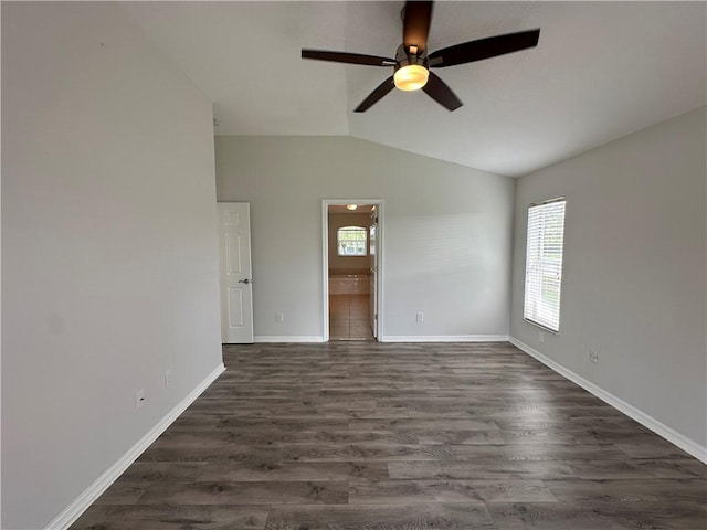 empty room featuring baseboards, lofted ceiling, a healthy amount of sunlight, and dark wood-style flooring