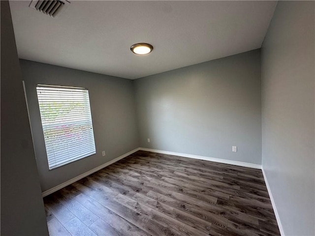 empty room featuring visible vents, wood finished floors, and baseboards