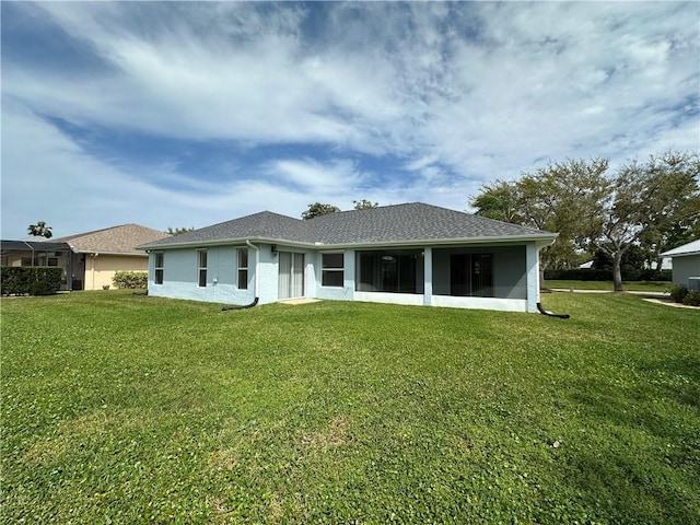 rear view of house with a yard, a sunroom, and stucco siding