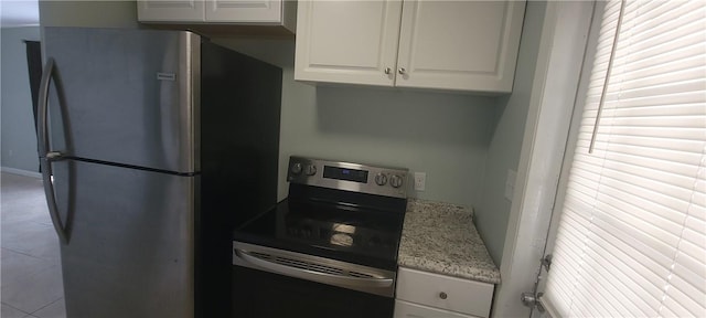 kitchen featuring white cabinetry, light tile patterned flooring, light stone counters, and appliances with stainless steel finishes