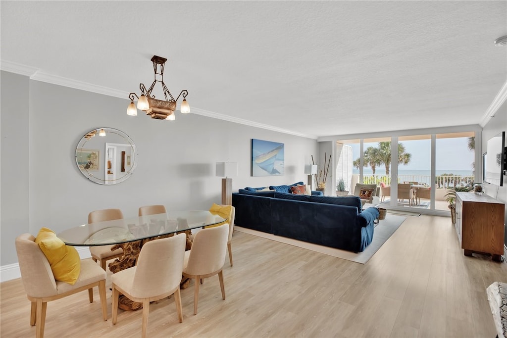 dining space with ornamental molding, an inviting chandelier, light hardwood / wood-style floors, and a textured ceiling