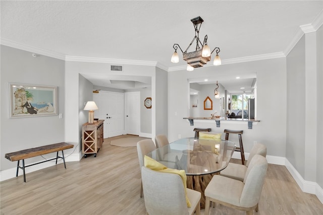 dining area with light hardwood / wood-style flooring and crown molding